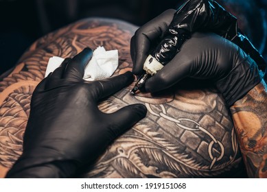 Shot Of A Tattoo Artist Hands Forming Perfect Lines On Man Back With Ink