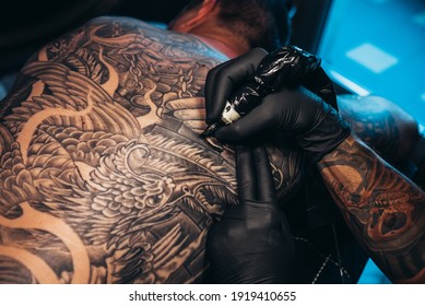 Shot Of A Tattoo Artist Hands Making A Permanent Tattoo On Man Back With His Machine