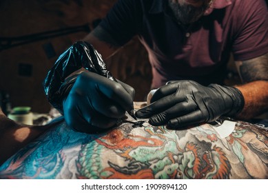 Shot Of A Tattoo Artist Hands While Tattooing Mans Back