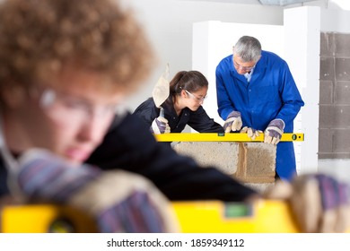 A shot of a teacher teaching a young girl how to use level tool in a bricklaying vocational school.