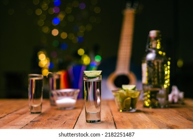 Shot Of Tequila Served In A Tequila Glass On A Wooden Table. Blurred Background. Rustic Bar Atmosphere.