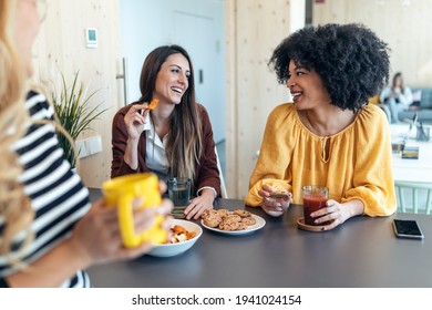 Shot of three smart entrepreneur women talking while taking a break and having a breakfast in the kitchen at coworking place.