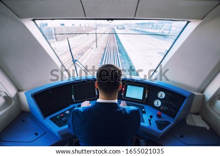 Shot of train cockpit interior with driver sitting and driving train.