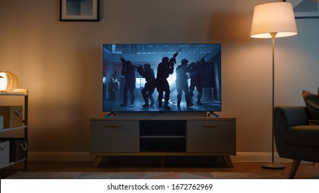 Shot of a TV with an Action Movie with Soldiers. It's Evening and Room at Home Has Working Lamps.