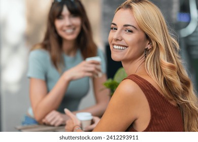 Shot of two attractive friends enjoying coffee together while talking and laughing sitting on the terrace of a bar. - Powered by Shutterstock