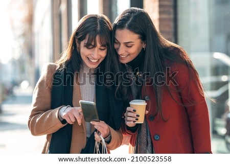 Shot of two beuatiful tourist friends consulting an online guide on a smart phone in the street.
