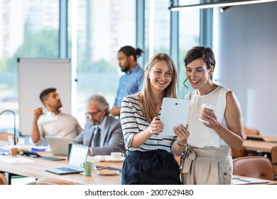 Shot Of Two Businesswomen Using A Digital Tablet Together During A Collaboration At Work.  Female Colleagues Looking At Tablet PC. Business People Are Working At Desk. 