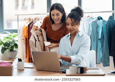 Shot of two fashion designers working with laptop and deciding details of clothes new collection in the sewing workshop. - Powered by Shutterstock