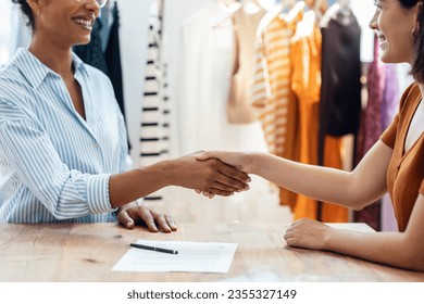 Shot of two fashion designers working with laptop while shaking hands after signing agreement contract in the sewing workshop. - Powered by Shutterstock