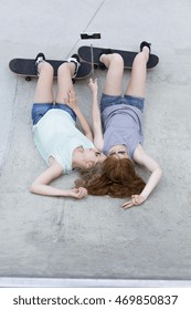 Shot Of Two Girls Taking Photo With A Selfie Stick While Lying On The Ground