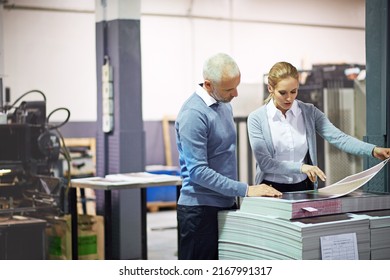 Shot of two managers looking over samples while standing inside a printing and packaging plant. The commercial designs displayed in this image represent a simulation of a real product and have been