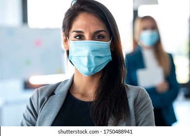 Shot of two pretty business women wearing a hygienic face mask while looking at camera in the coworking space. Social distancing concept. - Powered by Shutterstock