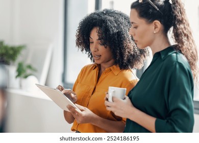 Shot of two smart pretty business women taking a break while cheaking her digital tablet standing in the office