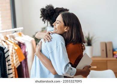 Shot of two smiling fashion designers women working while hugging each other in the sewing workshop. - Powered by Shutterstock