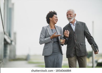 Shot of two successful multi-ethnic business people talking and having fun while walking during a coffee break outdoors.
