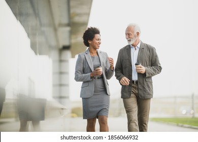 Shot Of Two Successful Multi-ethnic Business People Having Fun While Walking During A Coffee Break In Front Of The Office Building.