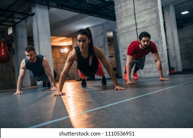 Shot of two young men and a woman standing in plank position at the gym - Shutterstock ID 1110536951