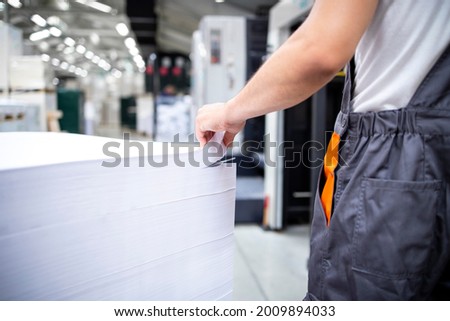 Shot of an unrecognizable print worker ready to place blank sheets of paper into offset machine for printing.