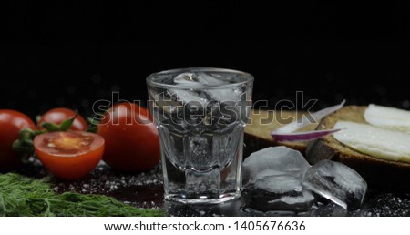 Shot of vodka in glass. Bread with lard, onion, dill and cherry tomatoes against black background