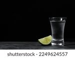 Shot of vodka with lime slice on grey table. Space for text