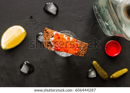 shot of vodka and a variety of snacks on a black background