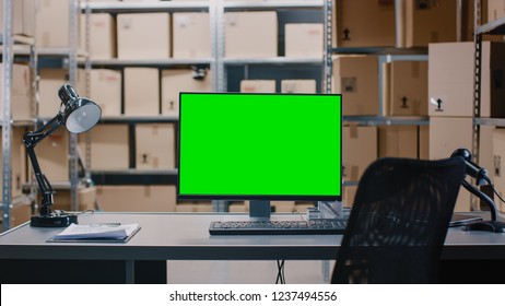 Shot Of A Warehouse Inventory Manager Desk And Personal Computer Wth Opened Spreadsheet. In The Background Shelves Full Of Cardboard Box Packages Ready For Shipping.