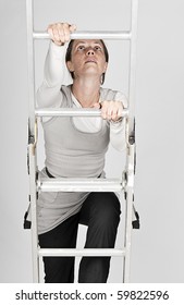 Shot of a Woman Climbing a Ladder against a Grey Background