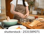 Shot of woman cracking an egg into a glass bowl