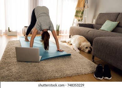 Shot Of A Woman Doing Exercise At Home With Her Dog