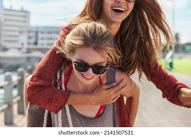 Shot Of A Woman Giving Her Friend A Piggy Back Ride