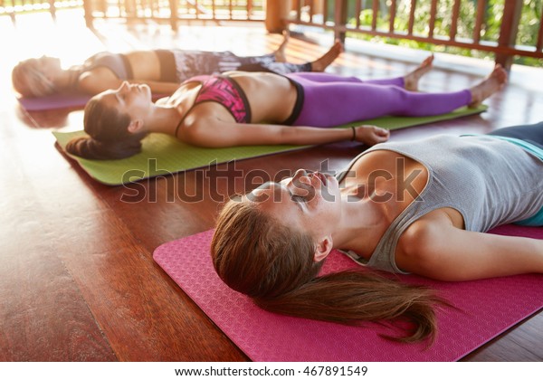 若い女性が床でくつろぐヨガ教室の撮影 死体のポーズで横たわるヨガ教室 サバサナ の写真素材 今すぐ編集