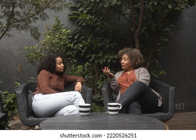 Shot of a young African-American woman bonding with her mother. They sit on the patio and have a coffee. - Powered by Shutterstock