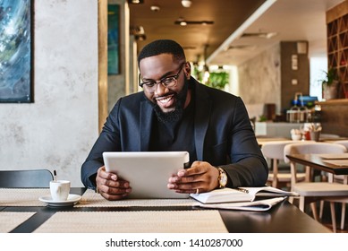 Shot of a young afro american businessman using tablet while resting in the cafe - Powered by Shutterstock