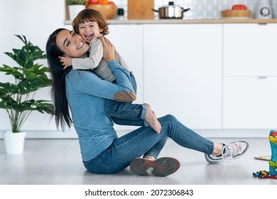 Shot of young beautiful mother playing and having fun on the floor with her son in living room at home. - Powered by Shutterstock