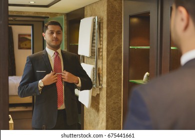 Shot of a young businessman dressing up in front of the mirror adjusting his jacket style fashion confidence masculinity elegance class luxury rich lifestyle wellbeing wealth clothing suit people men - Powered by Shutterstock