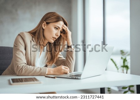 Shot of a young businesswoman looking stressed out while working in an office. Stressed business woman working from on laptop looking worried, tired and overwhelmed 