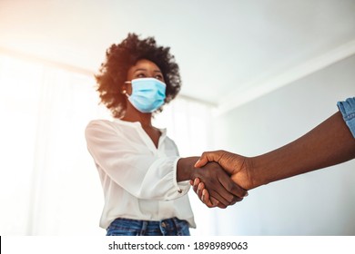 Shot of a young businesswoman with protective face mask shaking hands with a colleague in a modern office. Business colleagues with face masks greeting  - Powered by Shutterstock