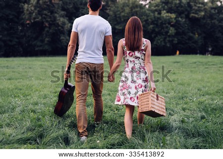 Shot of a young couple holding hands and finding a place for picnic. Selective focus.