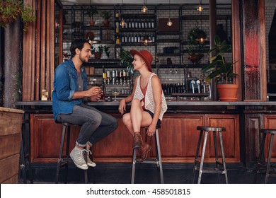 Shot of young couple sitting at cafe counter. Young man and woman at coffee shop. - Powered by Shutterstock