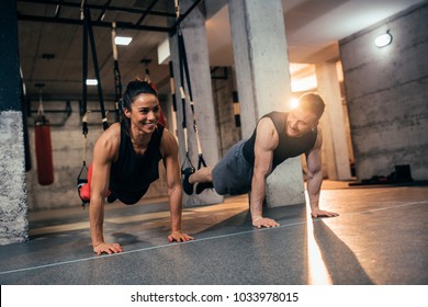 Shot of a young fit couple doing hanging straps push ups - Powered by Shutterstock