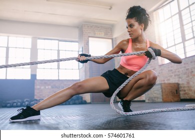 Shot Of Young Fitness Female Exercising With Rope At A Gym. Young Woman Pulling Rope At Gym.