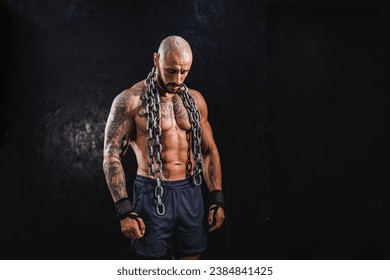 Shot of a young fitness man standing in the gym and posing before work out with a heavy chain around his neck. - Powered by Shutterstock