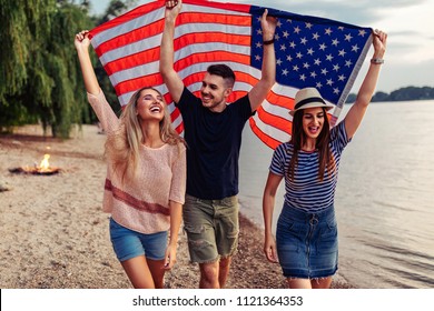 Shot of young friends carrying american flag on the beach - Powered by Shutterstock