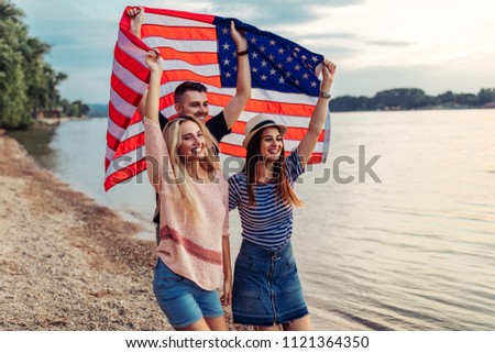 Shot of young friends carrying american flag on the beach
