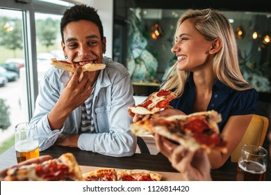 Shot Of A Young Happy Couple Eating Pizza In A Restaurant