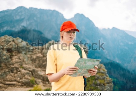 Shot of a young lost woman holding a map while taking in the view from the top of a mountain. Girl tourist in mountain read the map. Poland, Tatry 