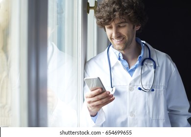 Shot Of A Young Male Doctor Using His Mobile Phone And Text Messaging. 