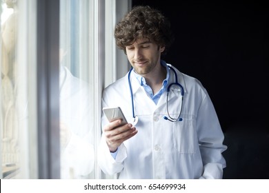 Shot Of A Young Male Doctor Using His Mobile Phone And Text Messaging. 