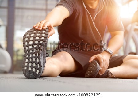 Shot of a young man stretching his legs before a gym workout