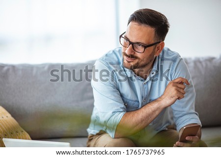 Shot of a young man using a smartphone on the sofa at home. What's the vibe on the newsfeed. Businessman holding smartphone for checking work or make appointment